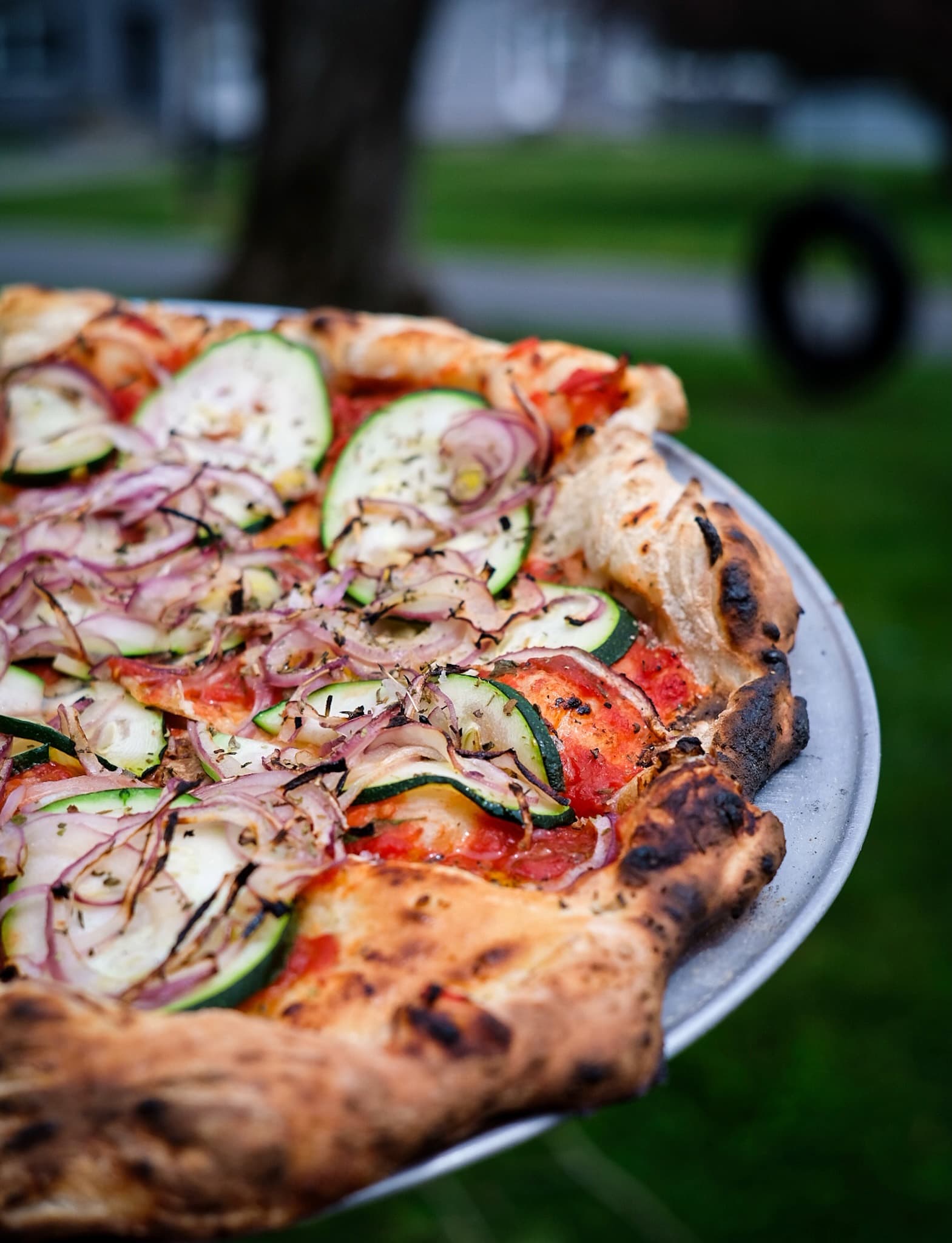 Zucchini, red onion and oregano pie with a blurred neighborhood behind